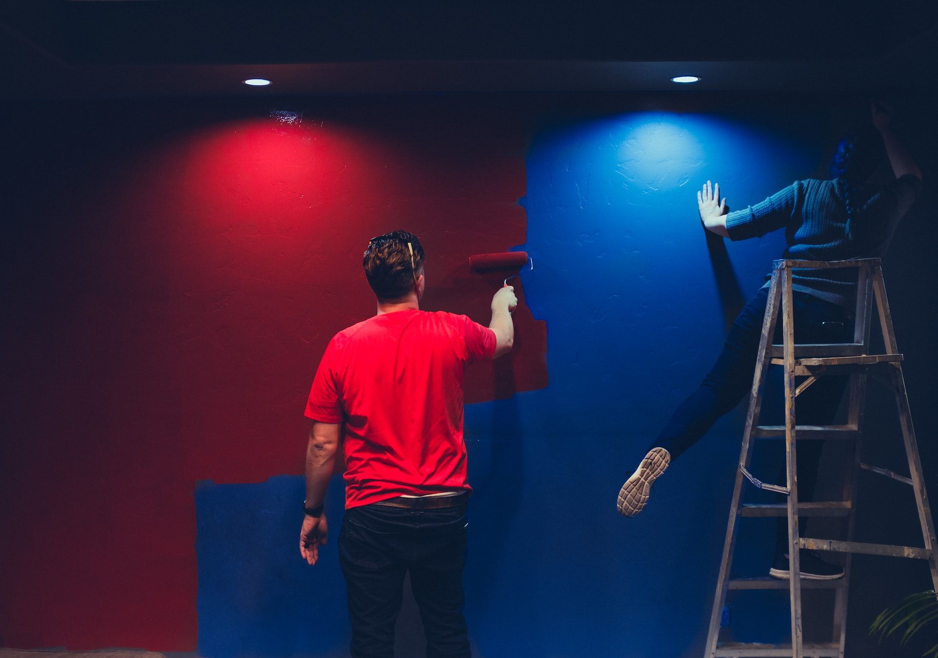 A man repainting a blue wall red